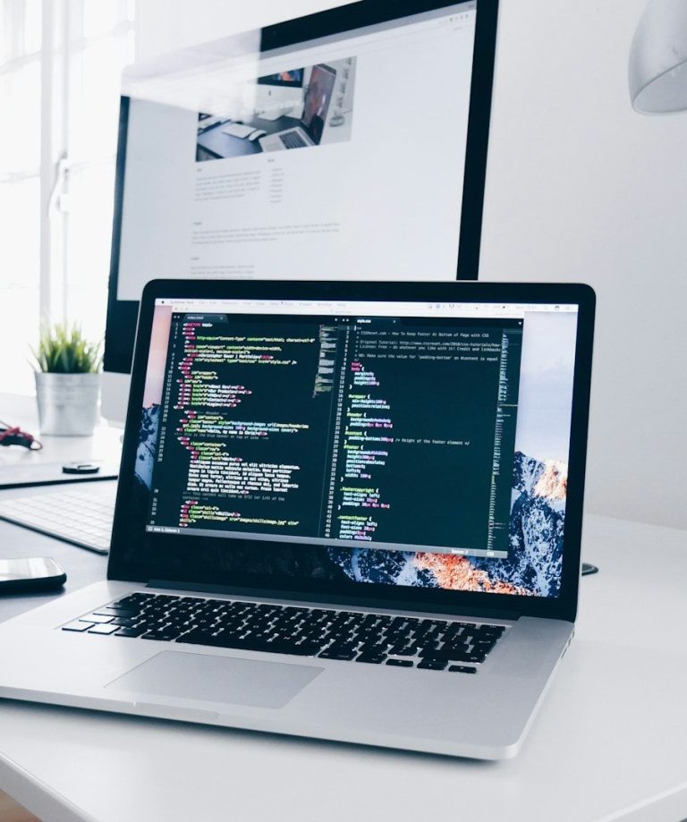 Picture of laptop computer and screen on a desk.
